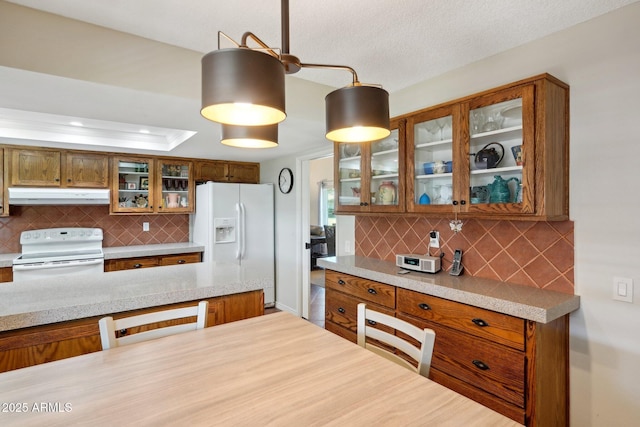 kitchen with backsplash, white appliances, hanging light fixtures, and a raised ceiling