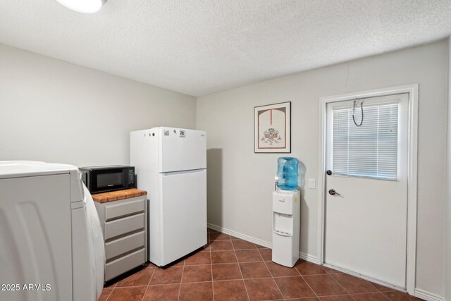 kitchen featuring white refrigerator, dark tile patterned floors, a textured ceiling, and washer / clothes dryer