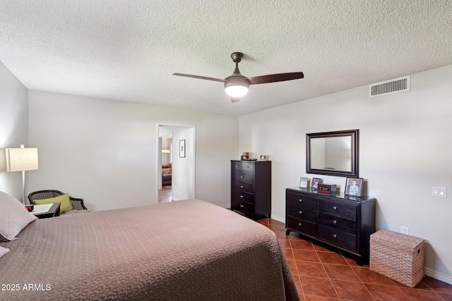 bedroom with ceiling fan, dark tile patterned flooring, and a textured ceiling