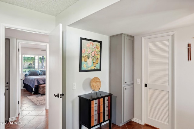 hallway featuring tile patterned flooring and a textured ceiling