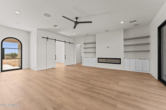 34256 S State Route 89th Hwy, Wickenburg, AZ 85390 - unfurnished living room featuring a barn door, a ceiling fan, light wood-style floors, recessed lighting, and baseboards