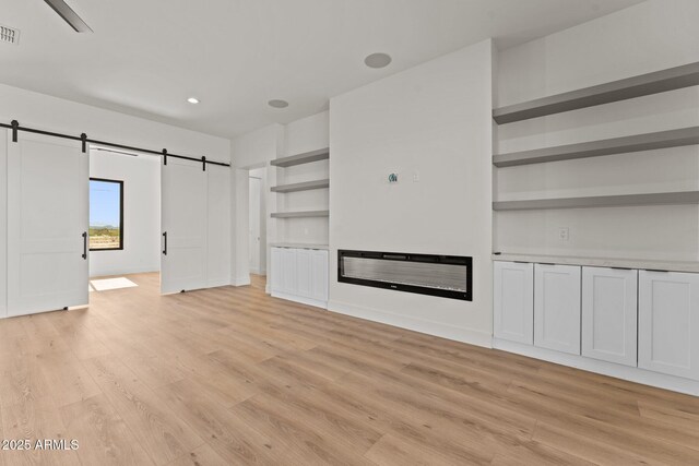 34256 S State Route 89th Hwy, Wickenburg, AZ 85390 - unfurnished living room featuring a barn door, light wood-style flooring, built in features, and recessed lighting