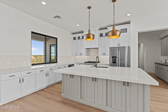 34256 S State Route 89th Hwy, Wickenburg, AZ 85390 - kitchen with stainless steel fridge, a sink, a center island with sink, light wood-style flooring, and backsplash