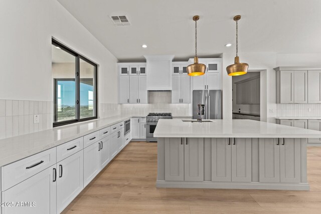 34256 S State Route 89th Hwy, Wickenburg, AZ 85390 - kitchen with appliances with stainless steel finishes, tasteful backsplash, light countertops, a sink, and an island with sink