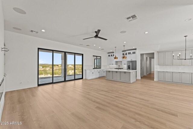 34256 S State Route 89th Hwy, Wickenburg, AZ 85390 - unfurnished living room with ceiling fan, light wood-style floors, a sink, a chandelier, and baseboards