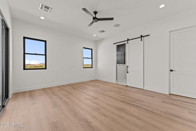 34256 S State Route 89th Hwy, Wickenburg, AZ 85390 - unfurnished bedroom featuring a barn door, light wood-type flooring, recessed lighting, and baseboards