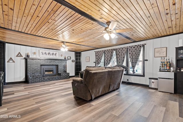 living room featuring a brick fireplace, wooden ceiling, ceiling fan, and wood finished floors