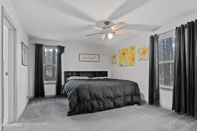 bedroom featuring multiple windows, a ceiling fan, baseboards, and carpet floors