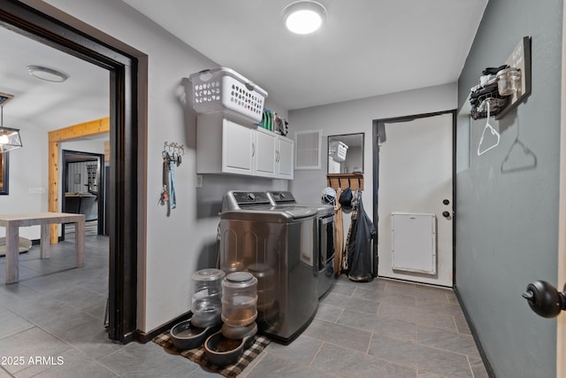 washroom with washer and dryer, cabinet space, and baseboards