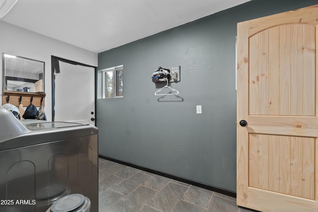 laundry room with laundry area, stone finish floor, washer / clothes dryer, and baseboards