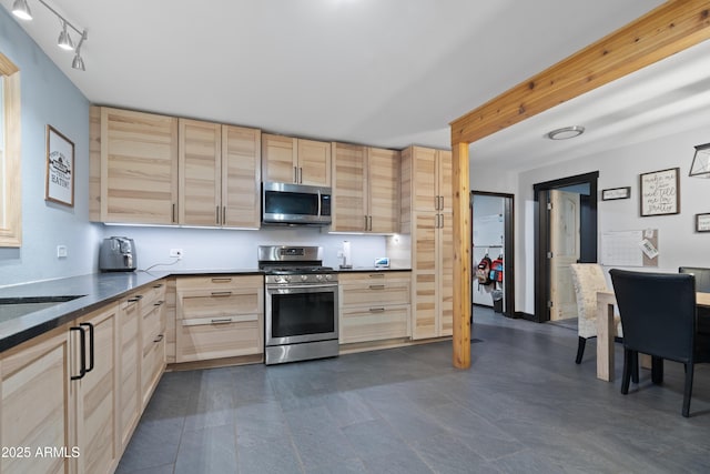 kitchen featuring dark countertops, light brown cabinets, and appliances with stainless steel finishes