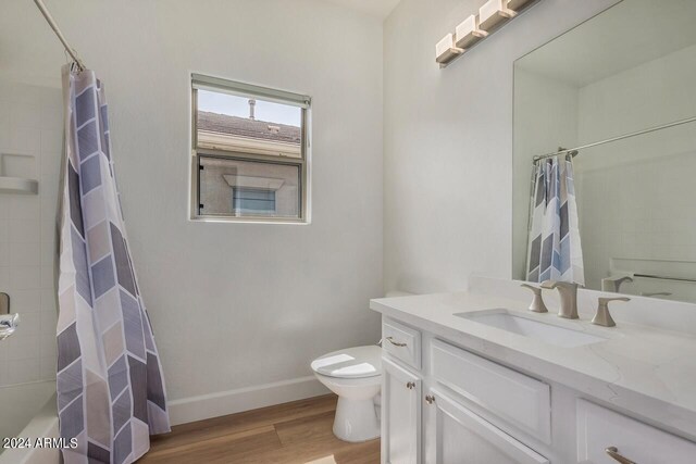 full bathroom with shower / tub combo with curtain, vanity, wood-type flooring, and toilet