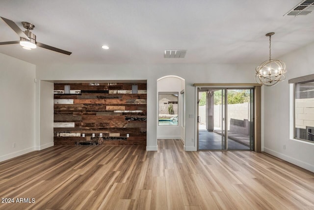 unfurnished living room with ceiling fan with notable chandelier and hardwood / wood-style flooring