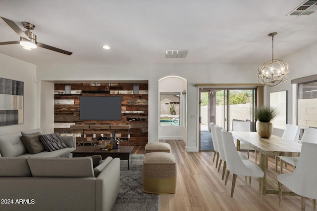 living room with ceiling fan with notable chandelier and light wood-type flooring