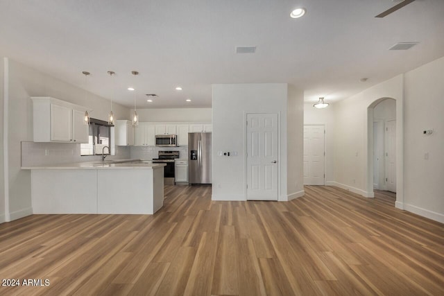 kitchen featuring white cabinetry, decorative backsplash, light hardwood / wood-style floors, appliances with stainless steel finishes, and kitchen peninsula