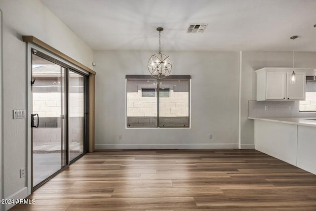 unfurnished dining area featuring a notable chandelier and hardwood / wood-style floors