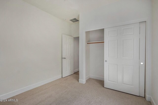 unfurnished bedroom with light carpet and a closet