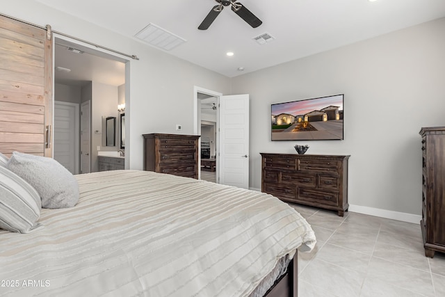 tiled bedroom with a barn door, connected bathroom, and ceiling fan