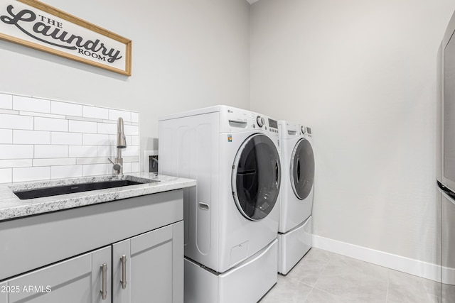 laundry area featuring light tile patterned flooring, cabinets, washer and clothes dryer, and sink