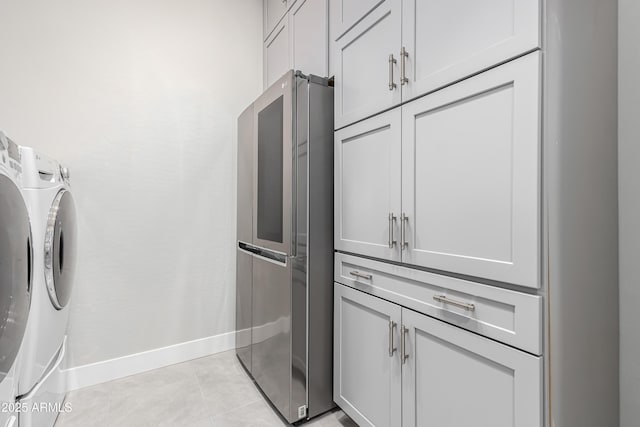 laundry area featuring light tile patterned flooring, cabinets, and washing machine and clothes dryer