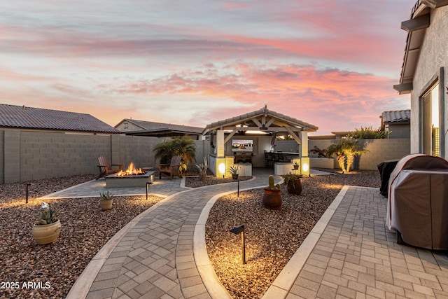 patio terrace at dusk featuring a gazebo, area for grilling, grilling area, and a fire pit