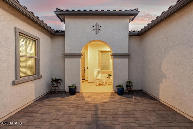 exterior entry at dusk featuring a patio area