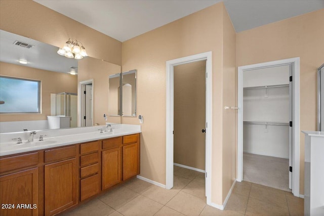 bathroom with tile patterned flooring, vanity, a shower with shower door, and a chandelier