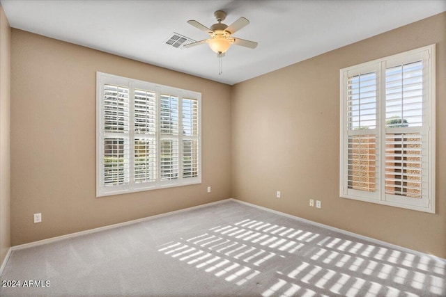 empty room with plenty of natural light, ceiling fan, and light carpet