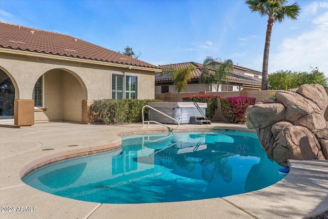 view of swimming pool featuring a patio and a hot tub