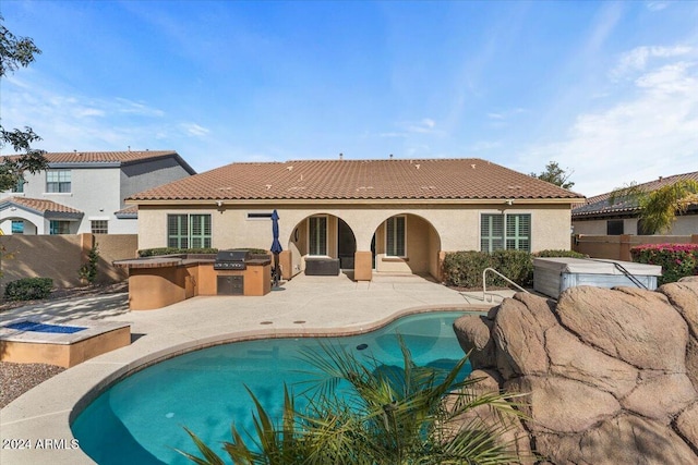 rear view of house with a patio area, exterior kitchen, and a fenced in pool