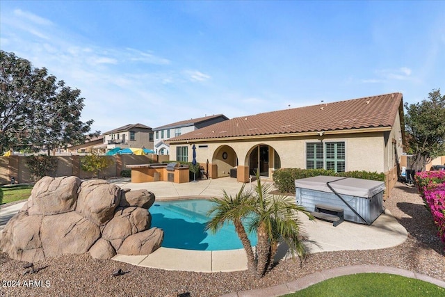 rear view of property featuring area for grilling, a patio area, and a pool with hot tub