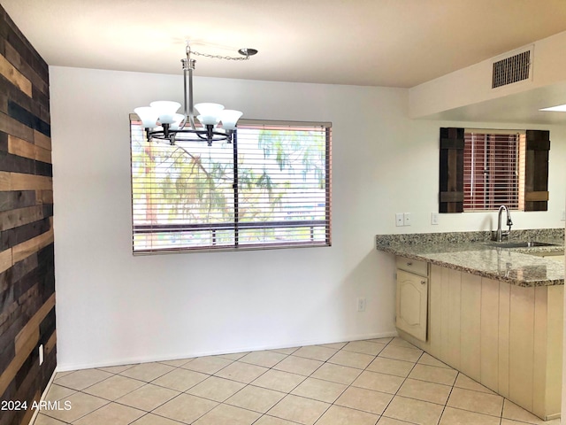 unfurnished dining area with sink, light tile patterned flooring, and an inviting chandelier