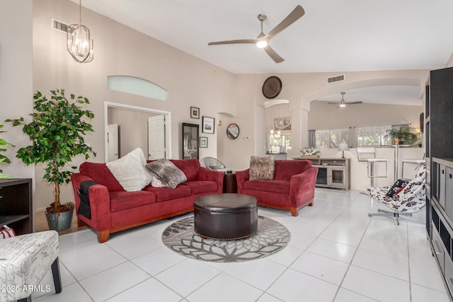 tiled living room featuring high vaulted ceiling and ceiling fan with notable chandelier