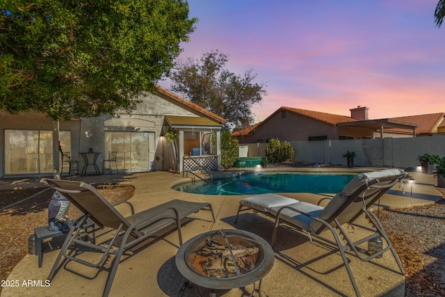 pool at dusk with a patio area and an outdoor fire pit