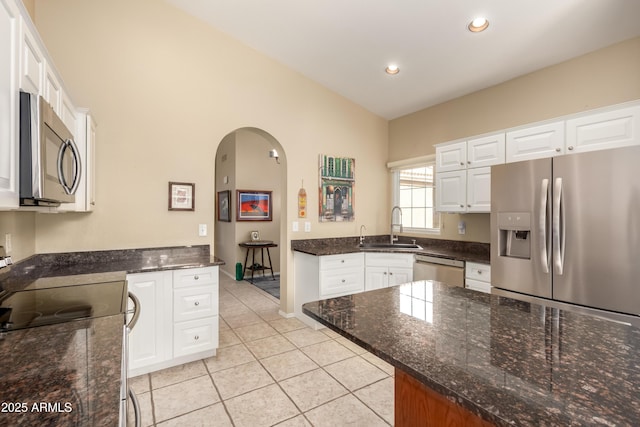 kitchen featuring white cabinets, stainless steel appliances, dark stone countertops, sink, and light tile patterned flooring