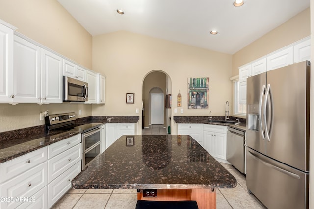 kitchen with sink, a center island, appliances with stainless steel finishes, and lofted ceiling