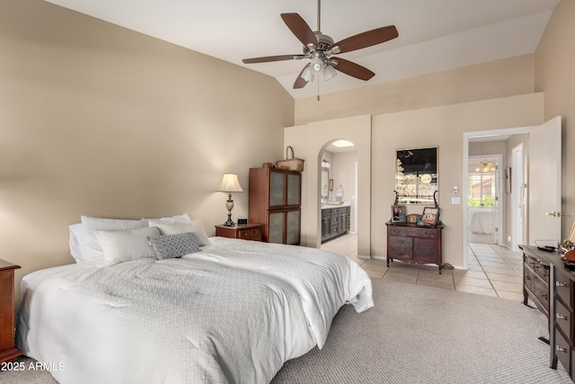 tiled bedroom featuring ceiling fan, ensuite bathroom, and vaulted ceiling