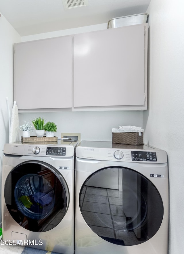 clothes washing area with cabinets and washer and dryer