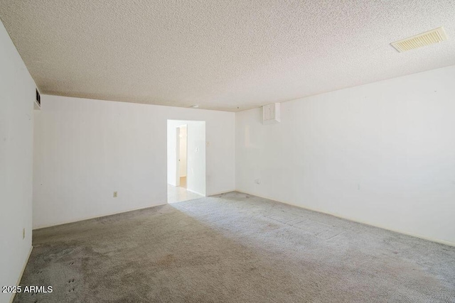 carpeted empty room with visible vents and a textured ceiling