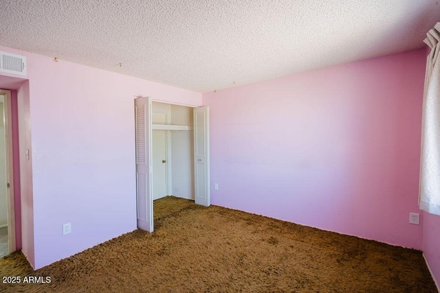 unfurnished bedroom featuring visible vents, carpet floors, a textured ceiling, and a closet