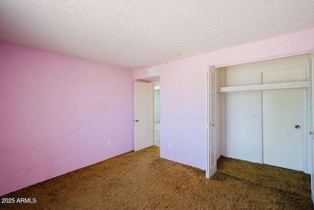 unfurnished bedroom with a closet, carpet flooring, a textured ceiling, and visible vents