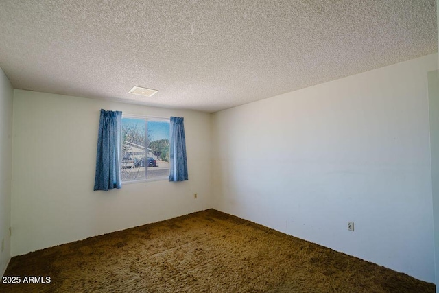 spare room featuring visible vents, a textured ceiling, and dark colored carpet