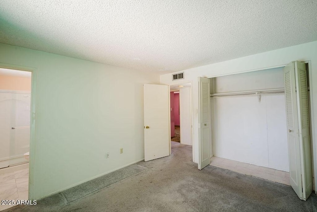 unfurnished bedroom with visible vents, a textured ceiling, a closet, and carpet flooring