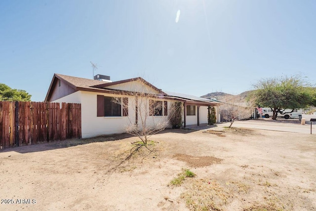 single story home with fence and roof mounted solar panels