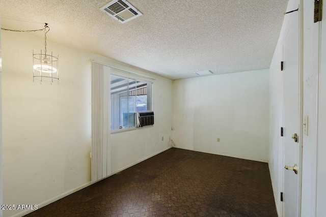 spare room with cooling unit, baseboards, visible vents, and a textured ceiling