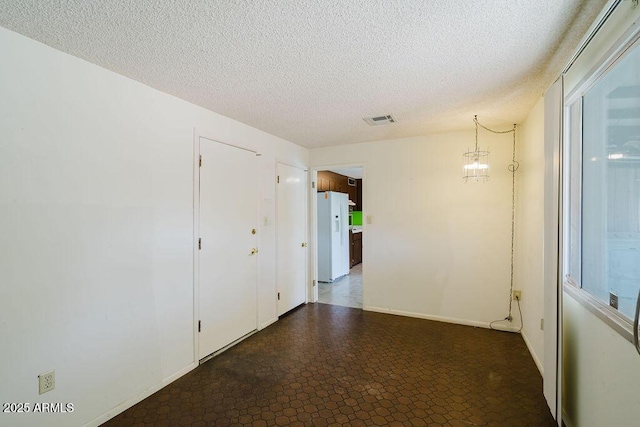 hall featuring visible vents, baseboards, a textured ceiling, and a notable chandelier