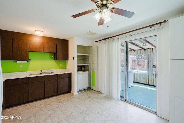 kitchen featuring visible vents, dark brown cabinetry, light countertops, a ceiling fan, and a sink