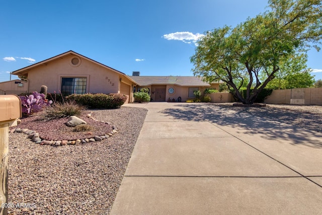 ranch-style house with concrete driveway, fence, stucco siding, and an attached garage