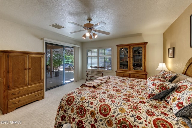 bedroom with a textured ceiling, visible vents, access to exterior, and light carpet