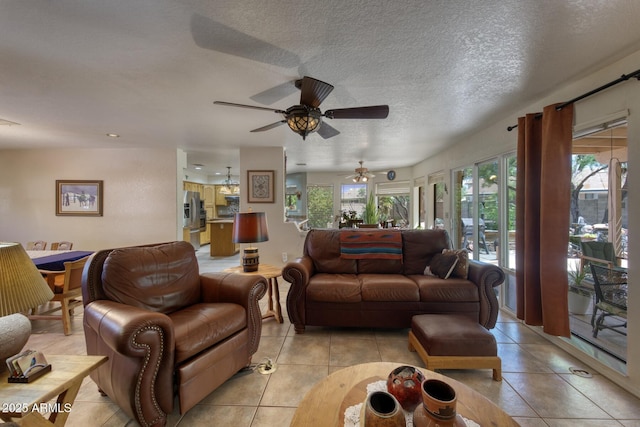 living area with light tile patterned floors, ceiling fan, and a textured ceiling